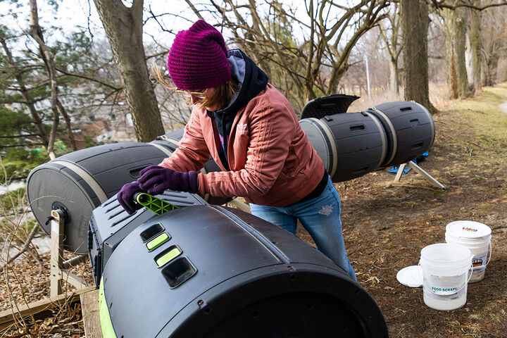 A student grabs the handle and turns one of several composting tumblers on the IU South Bend campus.